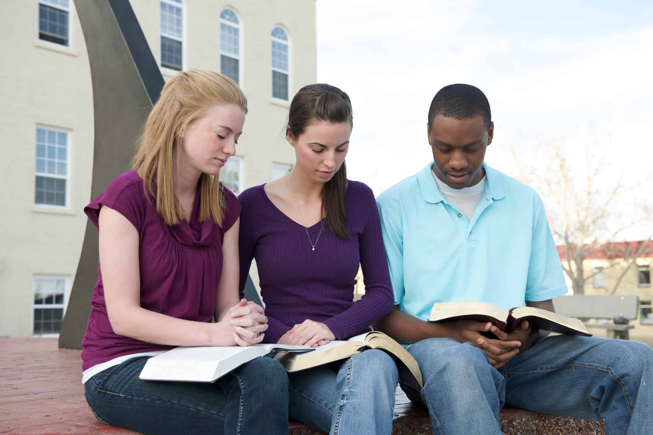 Three college students studying the Bible